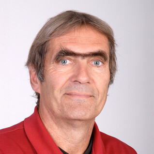 Portrait eines Mannes mit grauen Haaren und markanten Gesichtszügen.